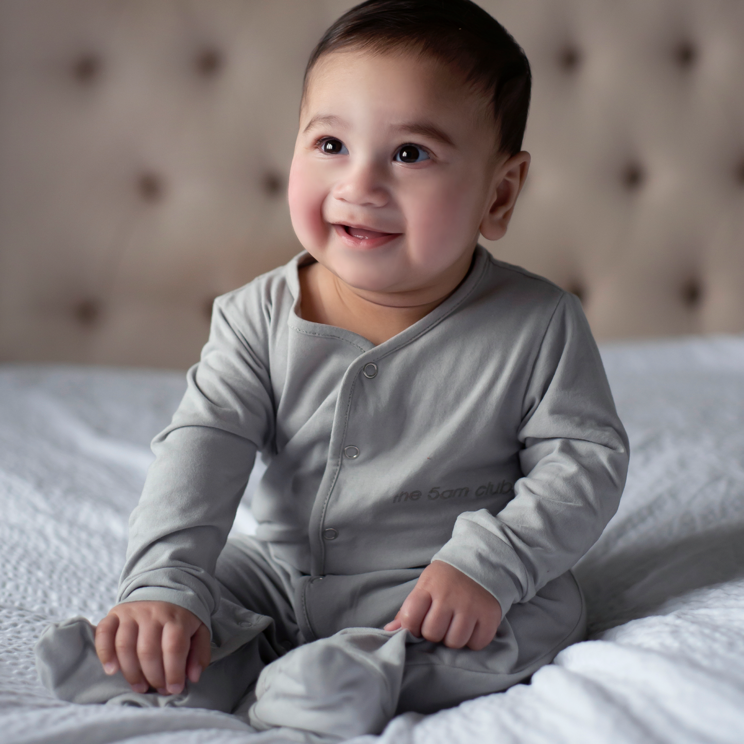 light grey babygrow with the 5am club logo on the chest and silver poppers down the front