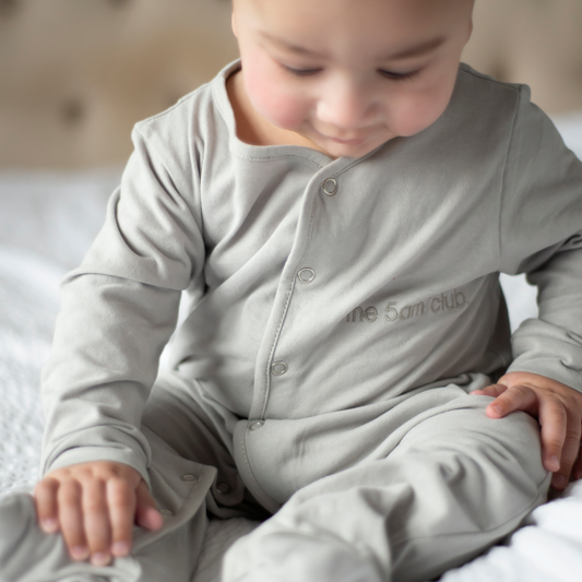 light grey babygrow with the 5am club logo on the chest and silver poppers down the front