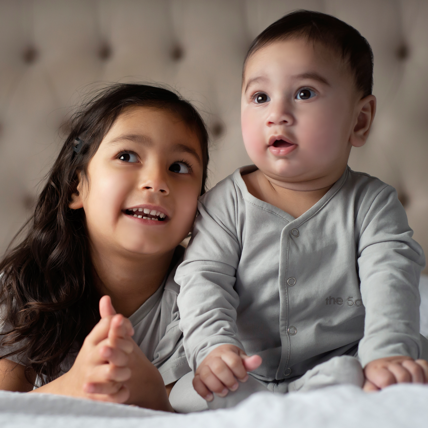 light grey babygrow with the 5am club logo on the chest and silver poppers down the front