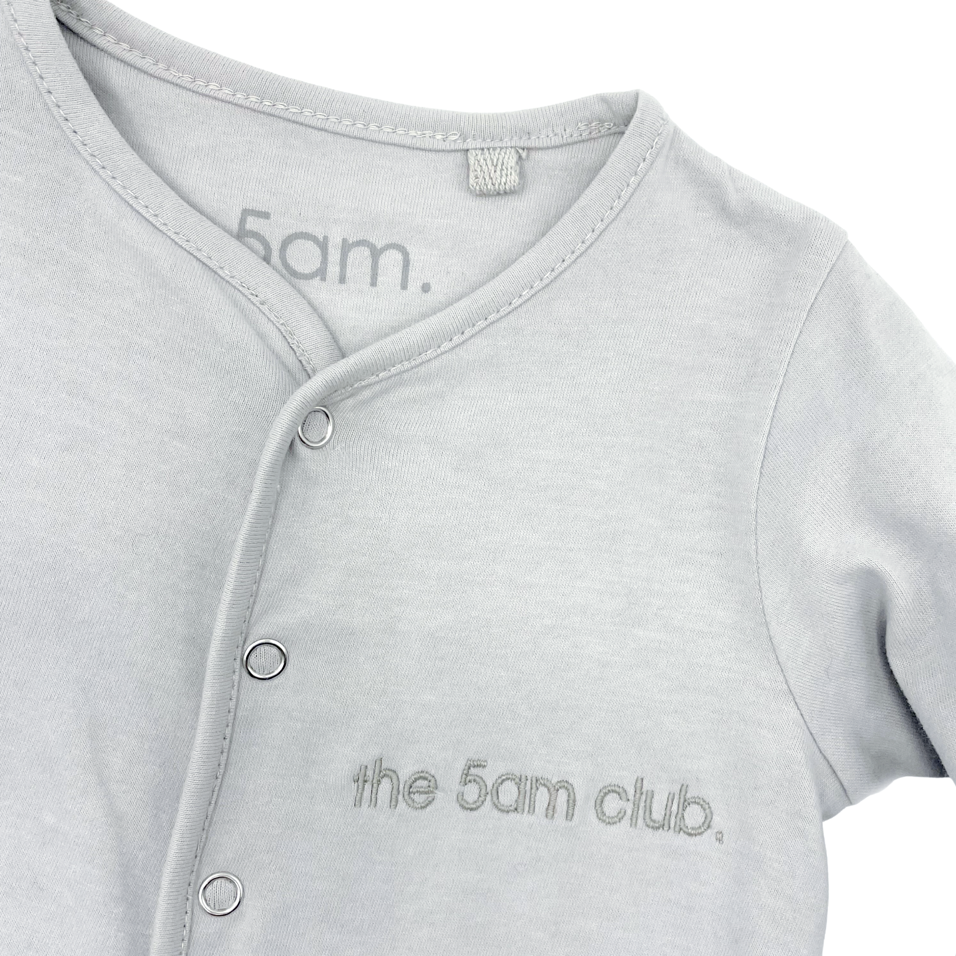 light grey babygrow with the 5am club logo on the chest and silver poppers down the front