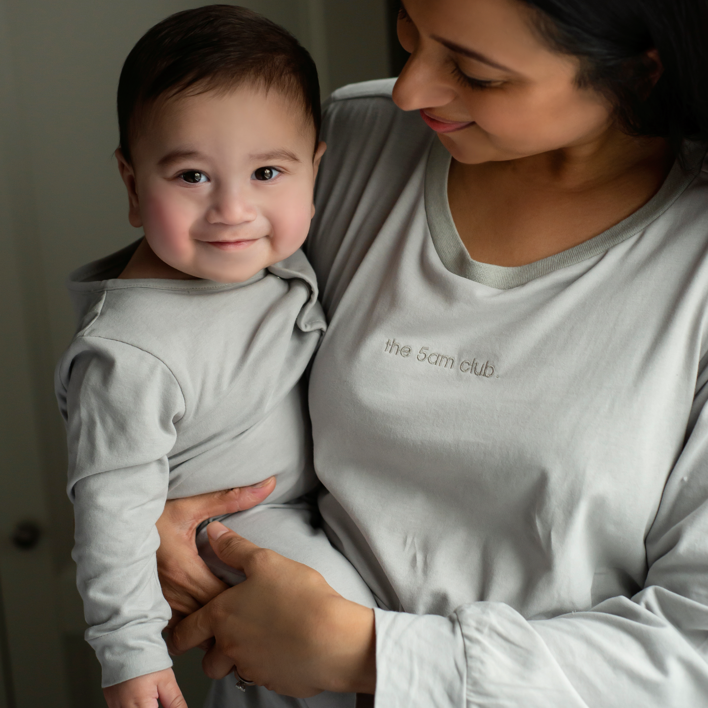 light grey babygrow with the 5am club logo on the chest and silver poppers down the front